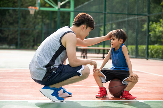 Happy father and son playing basketball on playground