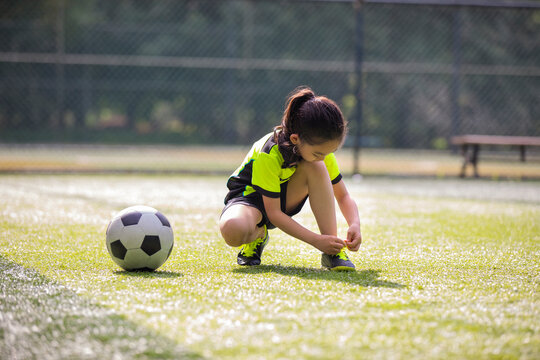 Little girl tying shoelace on soccer field