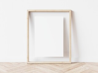 Blank vertically oriented rectangular picture frame with light wood border standing on wooden floor leaning on white wall. 3D Illustration. - obrazy, fototapety, plakaty