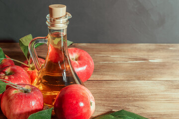 Homemade apple cider vinegar, cider, fruit juice in glass decanter with fresh red apples on wooden background with copy space for text