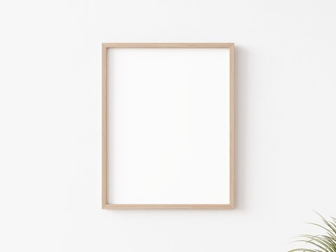 Single empty vertically oriented rectangular picture frame with thin wooden border hanging on white wall. 3D illustration.