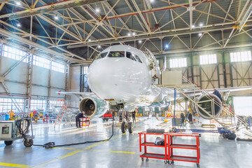 Aircraft inside the aviation hangar, maintenance service. Airplane technician worker working...