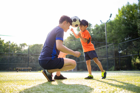Father and son playing football on field