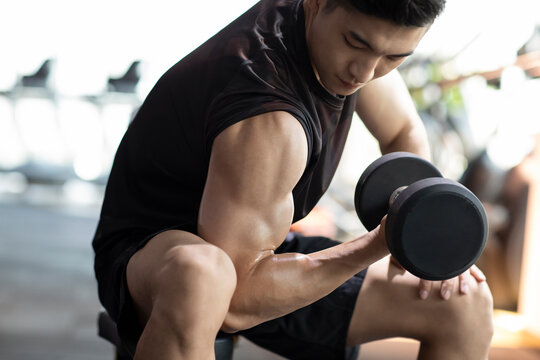 Young man working out with dumbbell at gym