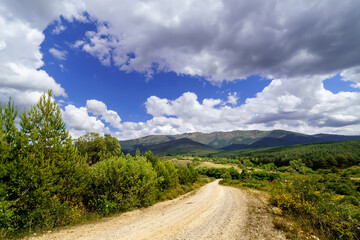 Fototapeta na wymiar Cloudscape on the mountain. Blue sky with clouds and dirt road to the mountain. 