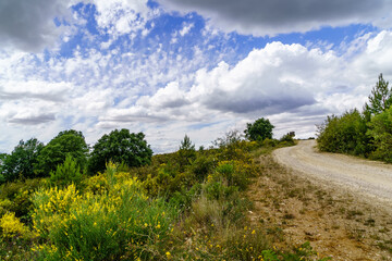 Fototapeta na wymiar Cloudscape on the mountain. Blue sky with clouds and dirt road to the mountain. 