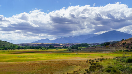 Fototapeta premium Cloudscape on the mountain. Blue sky with clouds and dirt road to the mountain. 