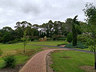 Beautiful morning view of a park with green grass, tall trees and dark cloudy sky, Fagan park, Galston, Sydney, New South Wales, Australia
