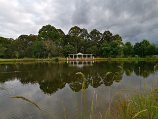 Beautiful morning view of a pond with reflections of trees and dark clouds on water, Fagan park, Galston, Sydney, New South Wales, Australia
