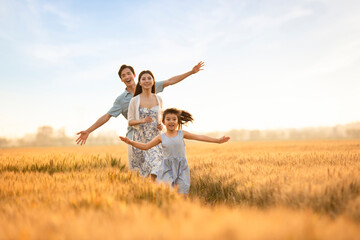 Happy young family having fun in wheat field