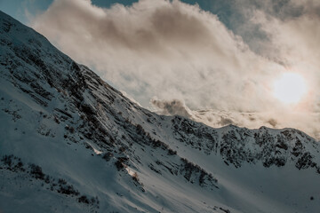 Fototapeta na wymiar Adler, Rosa Khutor. Clouds over snow-capped mountains.
