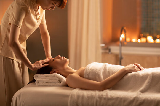 Young woman receiving facial massage at spa center