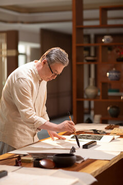 Senior man practicing calligraphy in the study