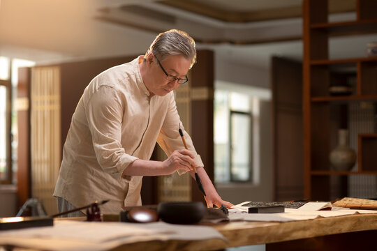 Senior man practicing calligraphy in the study