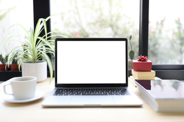 Laptop with coffee cup and gift box and book on wooden table
