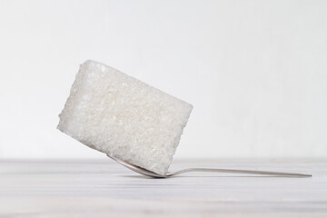 A huge lump of sugar on a teaspoon. White background. Copy space.