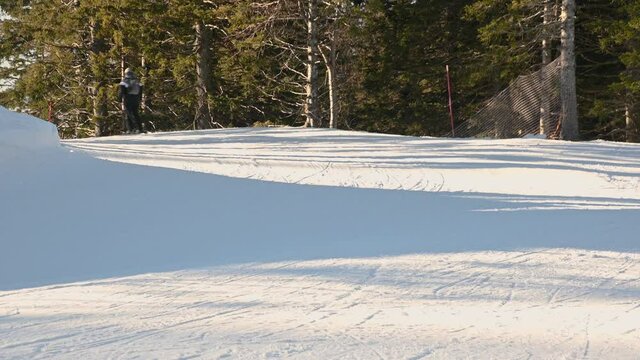 People skiing on ski track in winter season on curved slope. Activity on snow. Real time, static shot