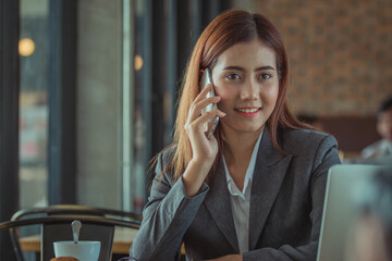 Portrait of an professional investment advisor businesswoman sitting in front of laptop at her desk while looking at camera and smiling.