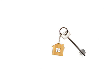 Key chain in the shape of wooden house with key on a white background, isolate. Building, design, project, moving to new home, mortgage, rent and purchase real estate, booking. Copy space