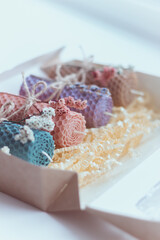 Gift set of four colored decorative natural beewax candles with dried flowers and a honey aroma for interior and tradition. A delicate color palette. Close up, selective focus.