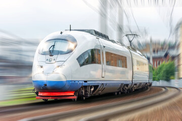 High-speed train with headlights on is driving through a corner at fast speed.