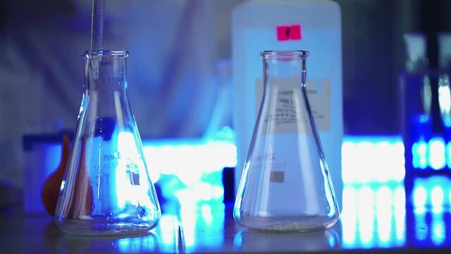 Scientist in laboratory doing chemical experiment with liquid in tube and flasks. Extraction DNA and molecules. Vaccine development. Research, biochemistry, pharmaceutical medicine concept. Close-up.