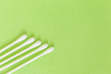 White cotton earbuds on pastel lime background, closeup	