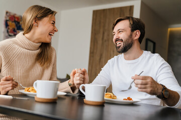 Beautiful young happy couple having breakfast