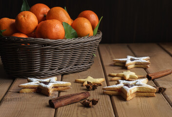 tangerines in a wicker basket, cookies and spices on a wooden table