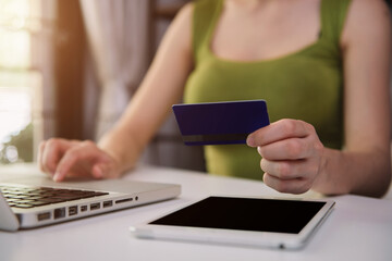 Women use credit cards to pay through tablet and laptop in office.