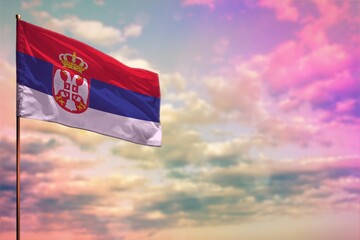 Fluttering Serbia flag mockup with the space for your content on colorful cloudy sky background.