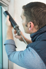 worker applying silicone sealant with silicone gun