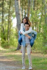 Obraz premium young carefree couple piggybacking and having fun among the trees