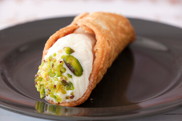 Sweety pastry called CANNOLO SICILIANO on a black dish