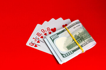 Money and cards on a red background. A combination of playing cards royal flush.