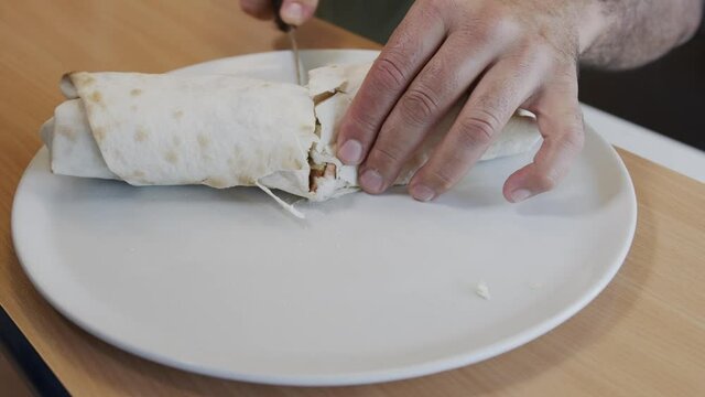 Traditional Turkish and Arabic street-style cheese kebabs served with yogurt, eggplant salad. durum doner kebab making. Chef cutting wrap in half a large knife.