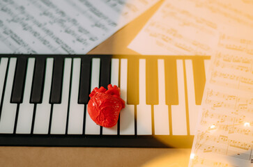 Heart on electronic keyboard piano with bokeh Christmas lights effect and note sheet in the...