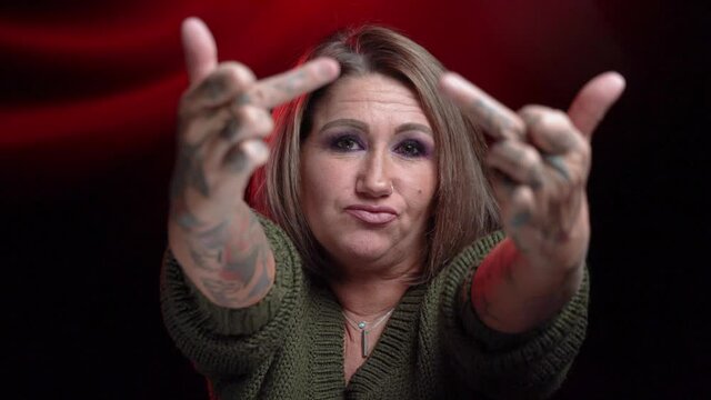 Tattooed mature woman flips of camera in slow motion and gives sassy look