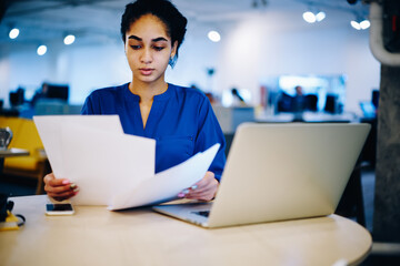 Busy ethnic businesswoman with paper and gadgets