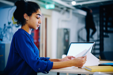 Young Indian woman with documents in workspace