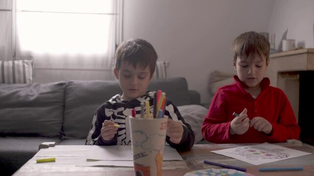 Caucasian kids painting mandala style draws, with coloured markers at home during coronavirus lockdown in Greece, Pan view 4K
