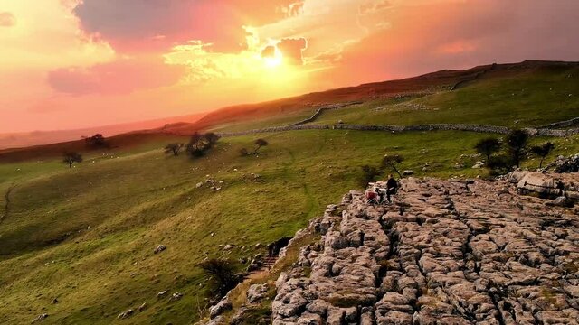 Sunset drone shot flying over drummer playing on rocks at Malham Cove