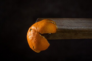 The tangerine peel hangs from the wooden surface. Citrus fruit. Mandarin zest