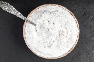 Fototapeta na wymiar Coconut flour in a bo Coconut flour in a bowl on a black table. View from abovewl on a black table. View from above