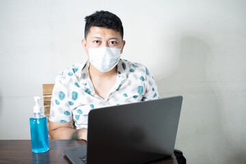 Business man using alcohol gel and wearing medical mask. has The computer page in front of. on...