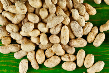 Peanuts in shell on a green board. Texture of nuts on a wooden old table. Lots of nuts in a pile.