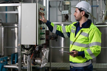 engineer or factory worker using tablet computer for finding how to use machine control panel in...