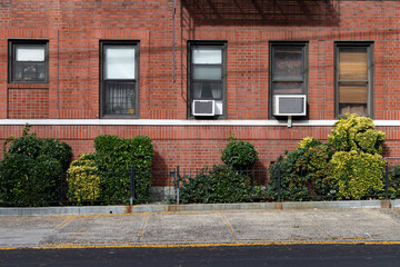 Empty Sidewalk next to an Old Brick Apartment Building with Window Air Conditioners in Astoria Queens New York