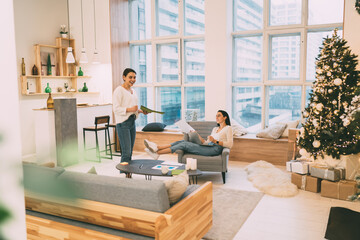 Smiling friends discussing project in cozy room with Christmas decorations