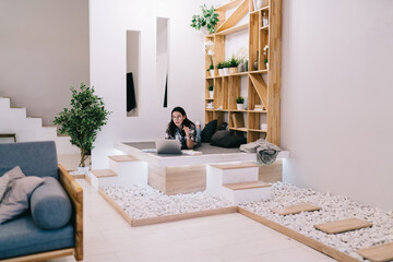 Young female employee working remotely in spacious apartment